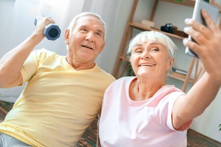 Senior couple exercise together at home health care selfie photos with dumbbellの写真素材