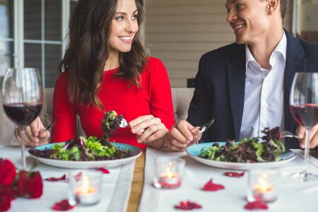 Young couple having romantic dinner in the restaurant eating talkingの写真素材