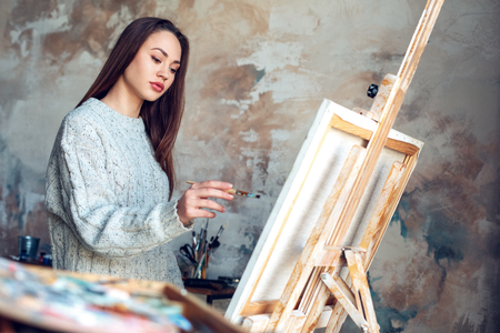 Young woman artist painting at home creative standing making abstract pictureの写真素材
