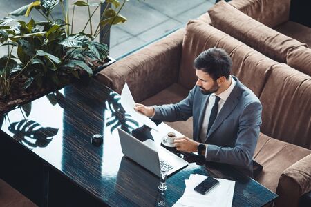 Businessman sitting in a business center restaurant drinking espresso reading top viewの写真素材