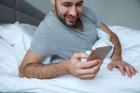 Bachelor man daily routine single lifestyle morning concept browsing smartphone close-upの写真素材