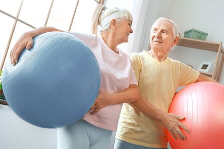 Senior couple exercise together at home health care carry balls looking on each otherの写真素材