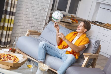 Man watching sport on tv at home alone playing with ballの写真素材