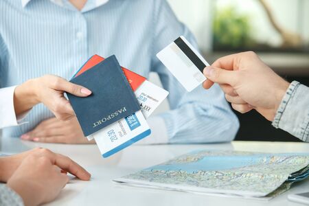 Young couple in a tour agency communication with a travel agent travelling concept credit card payment close-upの写真素材