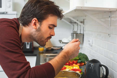Young man cooking romantic dinner at home chilling out soupの写真素材