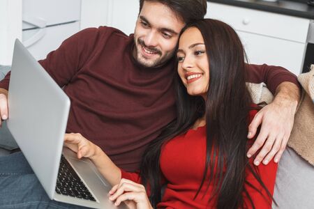 Young couple having romantic evening at home hugging watching movieの写真素材