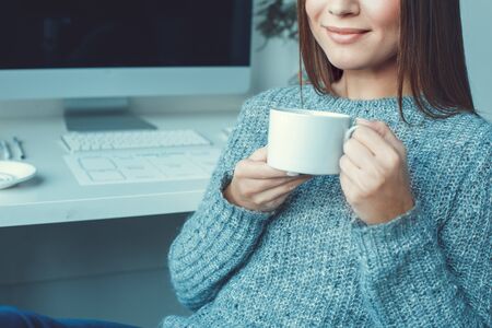 Young woman freelancer indoors home office concept casual style drinking tea close-upの写真素材