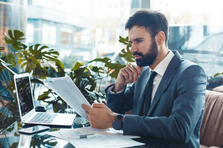 Businessman sitting in a business center restaurant reading contract concentratedの写真素材
