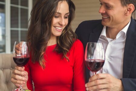 Young couple having romantic dinner in the restaurant hugging drining wine close-upの写真素材