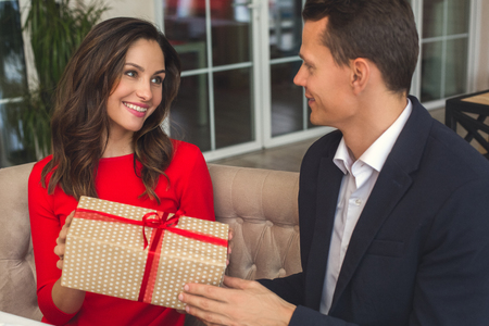 Young couple having romantic dinner in the restaurant holding a present gratefulの写真素材