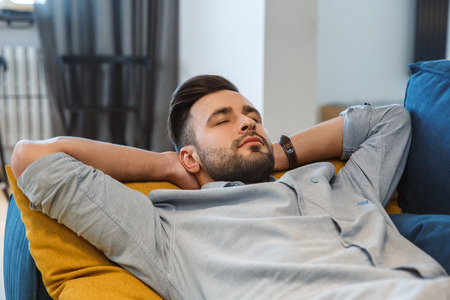 Bachelor man daily routine in the living room single lifestyle concept having nap close-upの写真素材