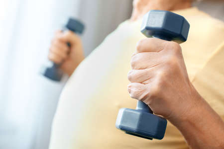 Senior man exercise at home health care with dumbbells body close-upの写真素材