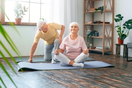 Senior couple doing yoga together at home health care butterfly pose smilingの写真素材