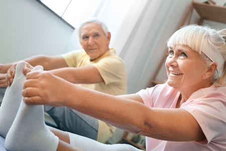 Senior couple doing yoga together at home health care legs stretching close-upの写真素材