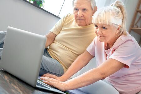 Senior couple exercise together at home health care watching training video