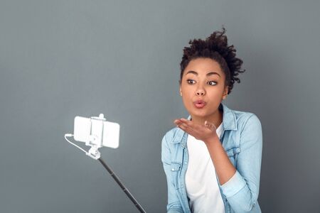 Young african woman isolated on grey wall studio casual daily lifestyle air-kissの写真素材