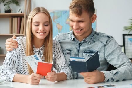 Young couple in a tour agency travelling concept holding documentsの写真素材