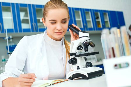 Young chemistry teacher in school laboratory workplace taking notesの写真素材