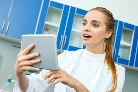 Young chemistry teacher in school laboratory work standing shockedの写真素材