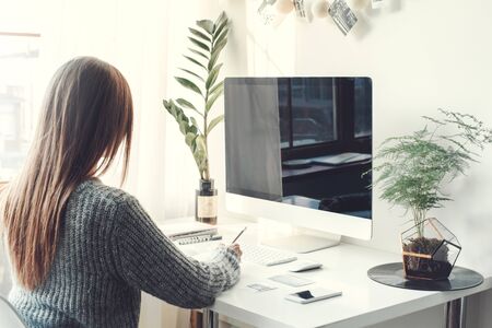 Young woman freelancer indoors home office concept casual style writingの写真素材