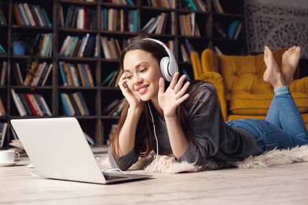 Young woman student in library at home lying video callの写真素材