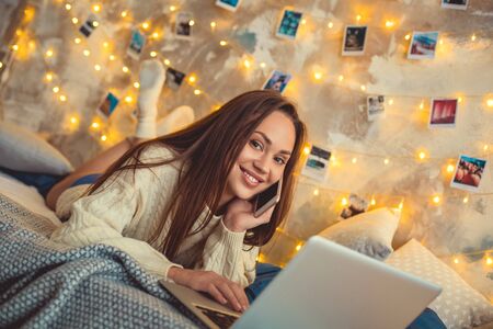 Young woman weekend at home decorated bedroom talking by smartphoneの写真素材