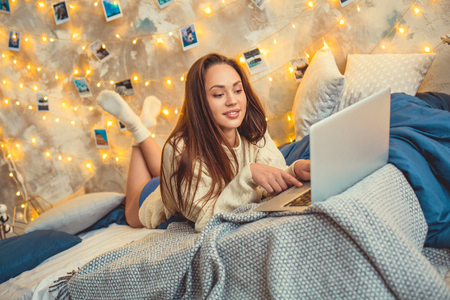 Young woman weekend at home decorated bedroom prepare for exam on laptopの写真素材