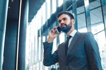 Businessman in a fromal suit in a business center phone callの写真素材