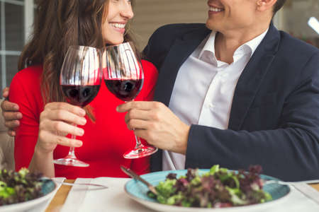 Young couple having romantic dinner in the restaurant cheers close-upの写真素材