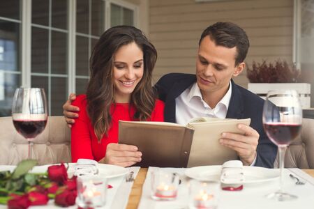 Young couple having romantic dinner in the restaurant holding menu concentratedの写真素材