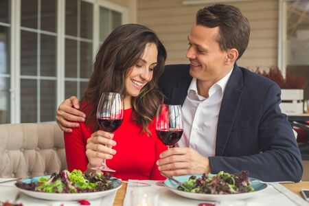 Young couple having romantic dinner in the restaurant hugging drining wineの写真素材