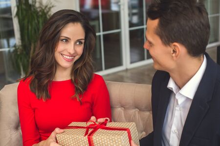 Young couple having romantic dinner in the restaurant holding a presentの写真素材