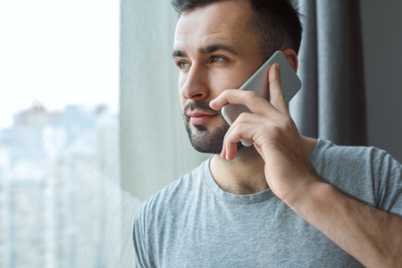 Bachelor man daily routine near the window single lifestyle concept phone call close-upの写真素材