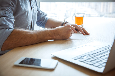 Bachelor man daily routine working from home single lifestyle concept writing close-upの写真素材