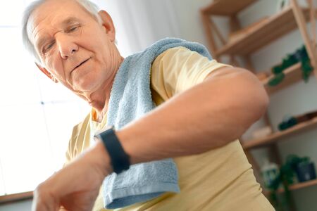 Senior man exercise at home health care checking time seriousの写真素材