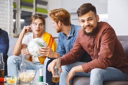Men watching sport on tv together at home man looking cameraの写真素材
