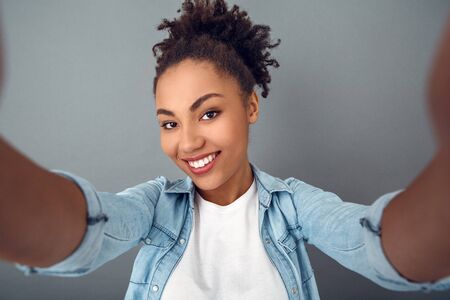 Young african woman isolated on grey wall studio casual daily lifestyle selfie close-upの写真素材