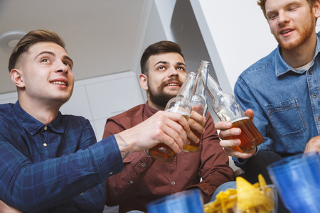 Men watching sport on tv together at home toast for team close-upの写真素材