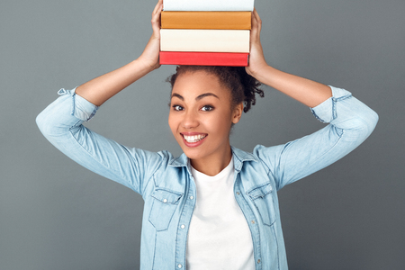 Young african woman isolated on grey wall studio casual daily lifestyle bookwormの写真素材