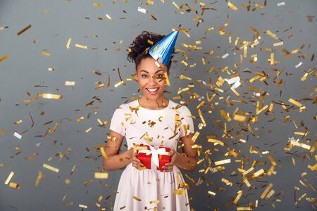 Young african woman isolated on grey wall studio celebration concept confetti burstの写真素材