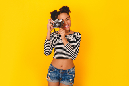 Young african woman isolated on yellow wall studio teen style taking photosの写真素材