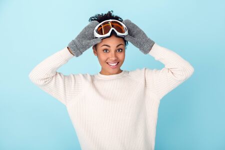 Young african woman isolated on blue wall studio winter sport concept preparationの写真素材