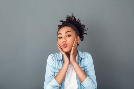 Young african woman isolated on grey wall studio casual daily lifestyle kissの写真素材