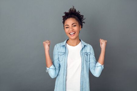 Young african woman isolated on grey wall studio casual daily lifestyle winnerの写真素材