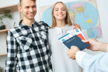 Young couple in a tour agency communication with a travel agent travelling concept giving documentsの写真素材