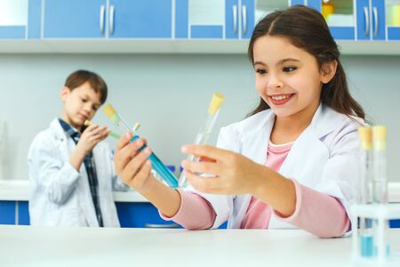 Little kids learning chemistry in school laboratory comparing liquidsの写真素材