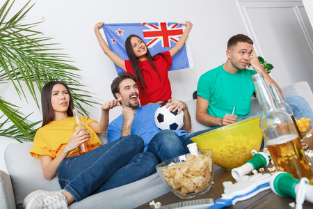 Group of friends sport fans watching match in colorful shirts concernedの写真素材