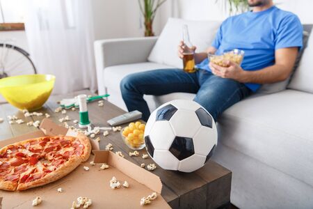 Young man sport fan watching match in a blue t-shirt table close-upの写真素材