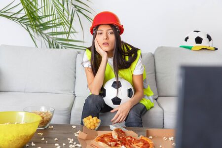 Young woman builder sport fan watching match boredの写真素材