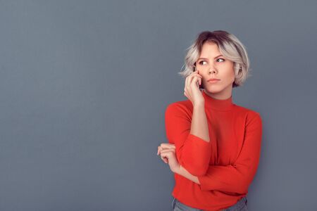 Young woman in a red blouse isolated on grey wall phone call replyの写真素材